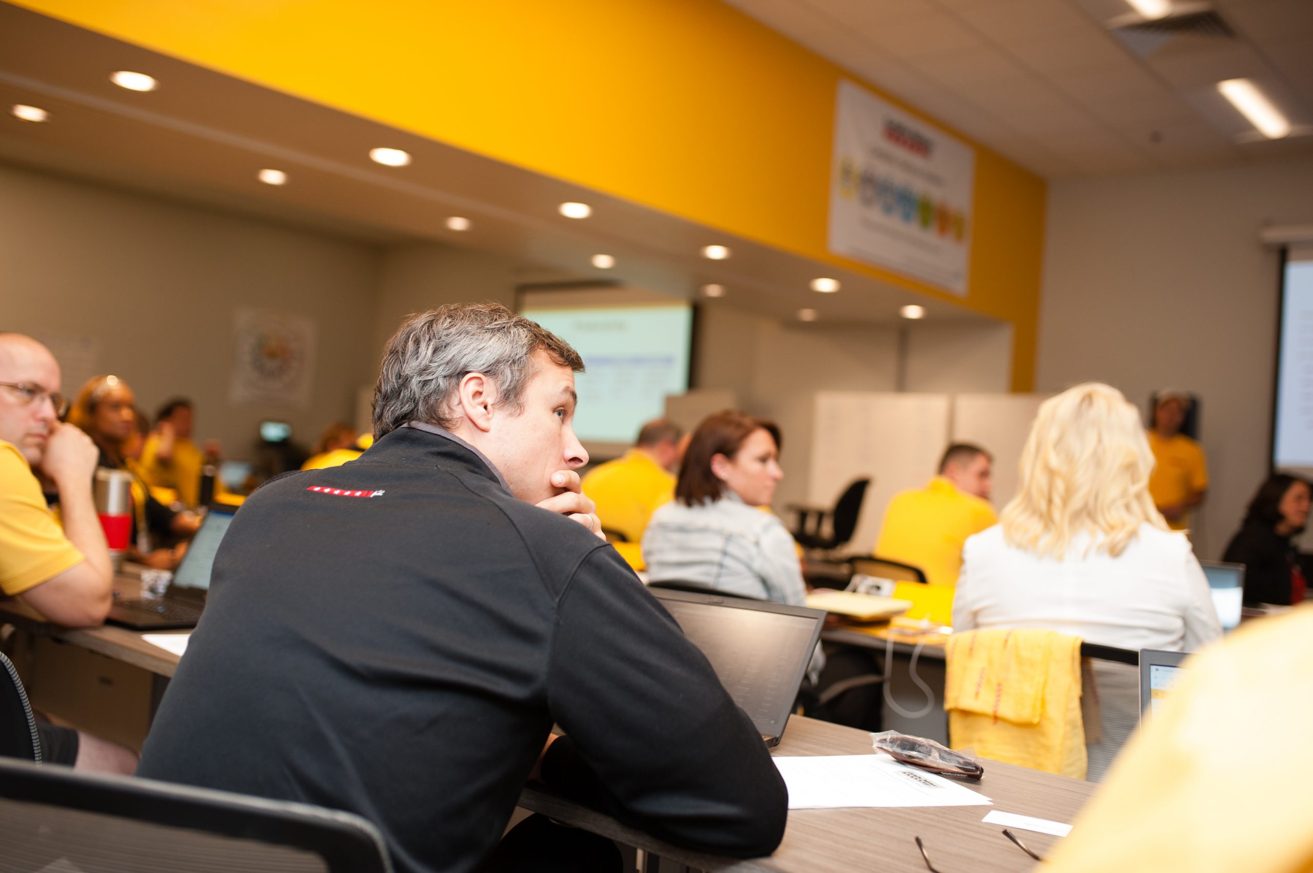 Attendee listens to a presenter in a room full of other attendees at CertaPro Painters headquarters.