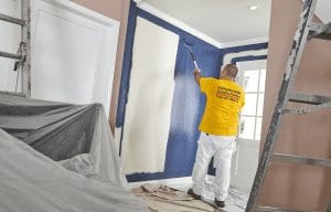 Painter for CertaPro Painters painting a wall blue.